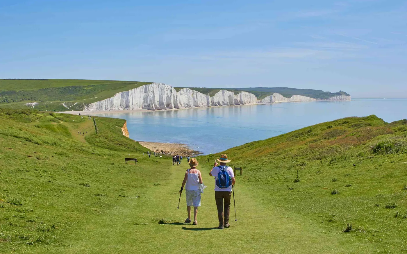 Couple walking in a field with the ocean in the background